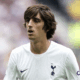 Bryan Gil in Tottenham white, with a faded montage of Valencia, Sevilla, and Girona crests, reflecting his loan-laden career